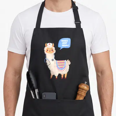 Wound alpaca apron - Cartoon alpaca in nurse hat with stethoscope and speech bubble text — shown on a black cotton canvas apron against a white background
