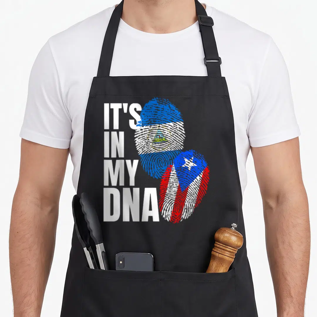 Nicaraguan puerto heritage aprons - IT'S IN MY DNA text beside Nicaraguan and Puerto Rican flag fingerprints — shown on a black cotton canvas apron against a white background