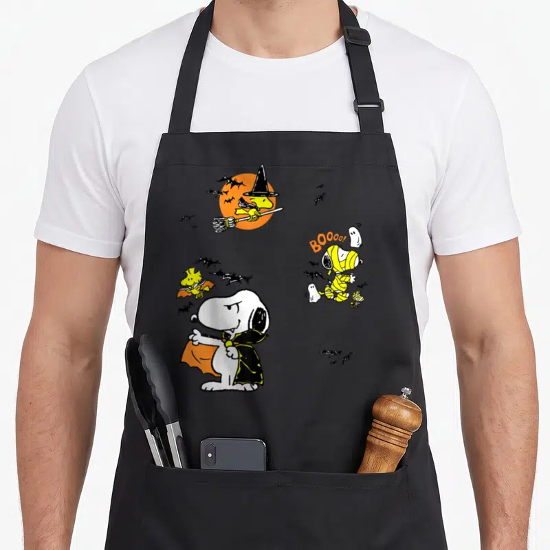 Funny woodstock halloween apron - Snoopy vampire mummy Woodstock witch bat orange moon black bats white ghosts cartoon — shown on a black cotton canvas apron against a white background
