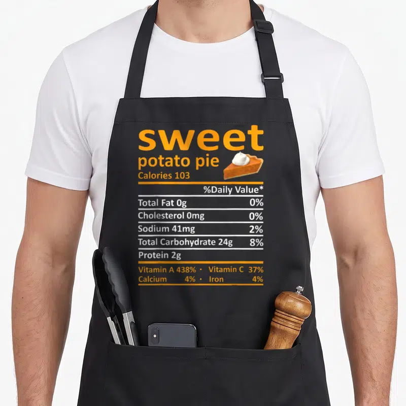 Sweet pie apron - Orange and white nutrition label for sweet potato pie with a slice topped with cream — shown on a black cotton canvas apron against a white background