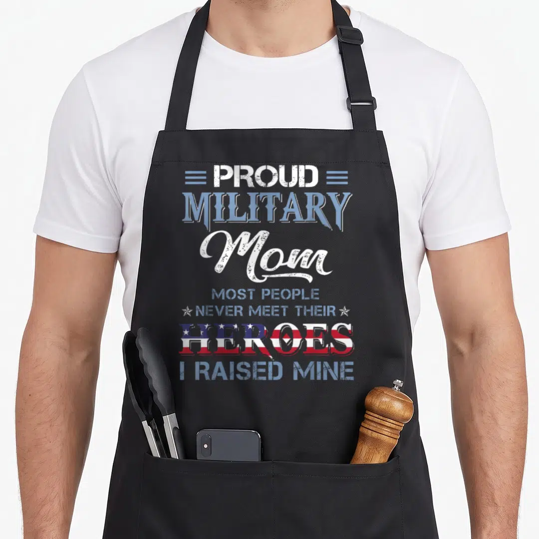 Hero military apron - Proud Military Mom text with heroes filled in US flag pattern and stars — shown on a black cotton canvas apron against a white background