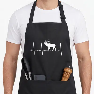 Heartbeat elk apron - White elk silhouette integrated into a horizontal heartbeat line on black fabric — shown on a black cotton canvas apron against a white background