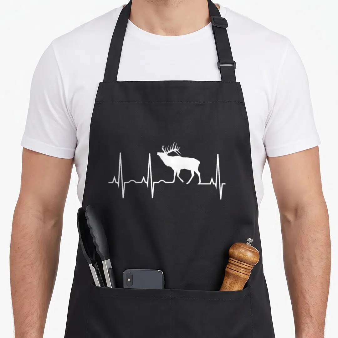Heartbeat elk apron - White elk silhouette integrated into a horizontal heartbeat line on black fabric — shown on a black cotton canvas apron against a white background