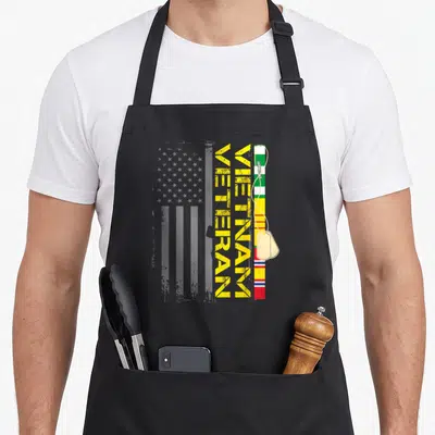 Vietnam us aprons - Grey flag, vertical yellow VIETNAM VETERAN text, service ribbons, and dog tags in distressed style — shown on a black cotton canvas apron against a white background