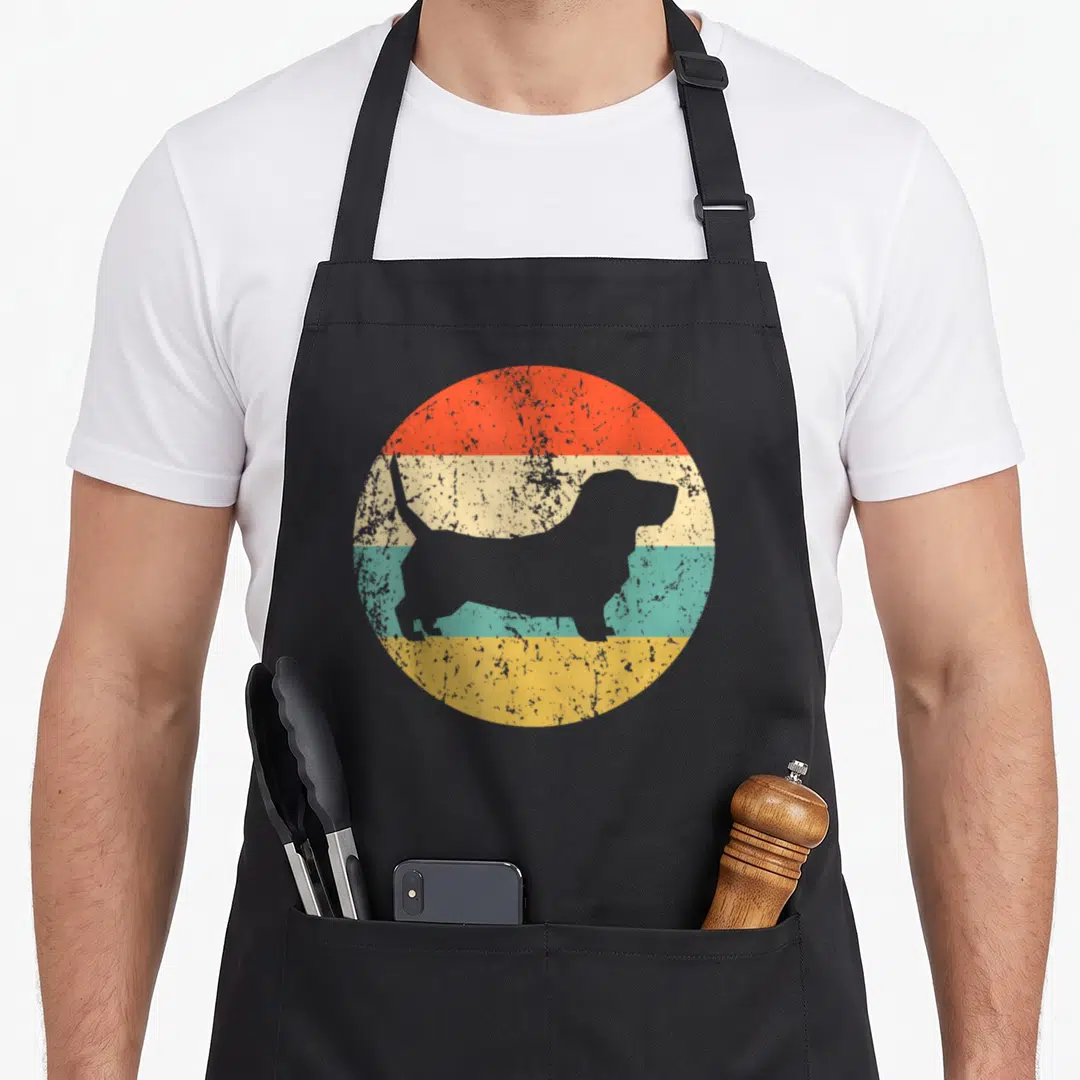 Hound dog apron - Grey basset hound silhouette on red cream teal yellow striped circle — shown on a black cotton canvas apron against a white background