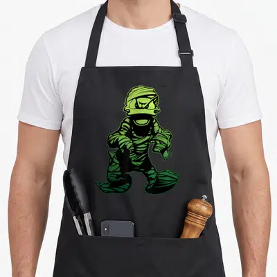 Costume mummy and me aprons - Cartoon mummy in lime green and black bandages walking forward — shown on a black cotton canvas apron against a white background