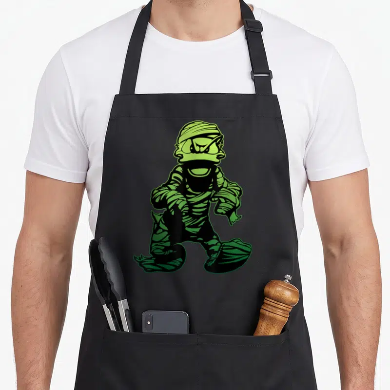 Costume mummy and me aprons - Cartoon mummy in lime green and black bandages walking forward — shown on a black cotton canvas apron against a white background