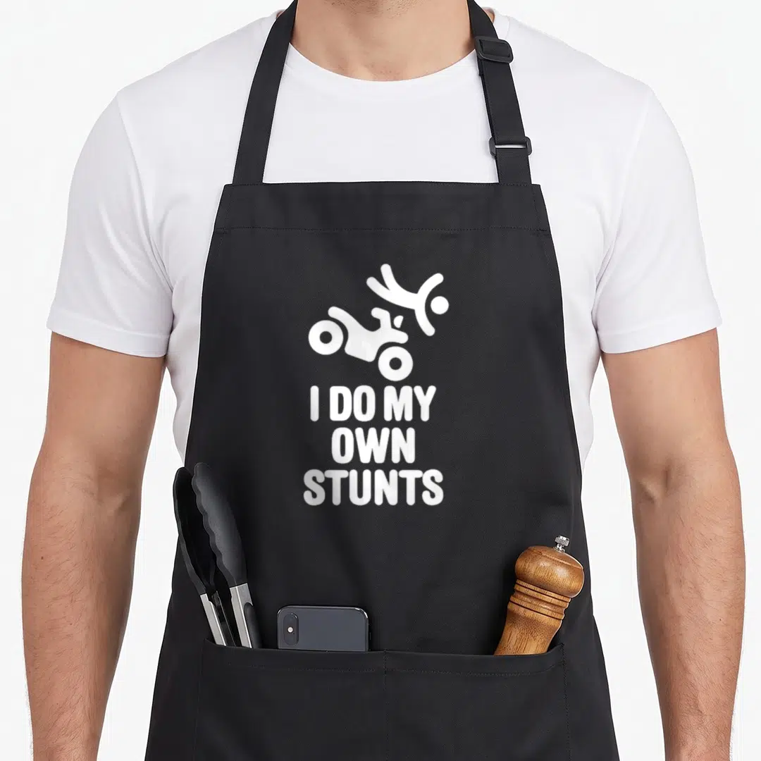 Stunt vehicle apron - White falling rider silhouette above I DO MY OWN STUNTS text — shown on a black cotton canvas apron against a white background