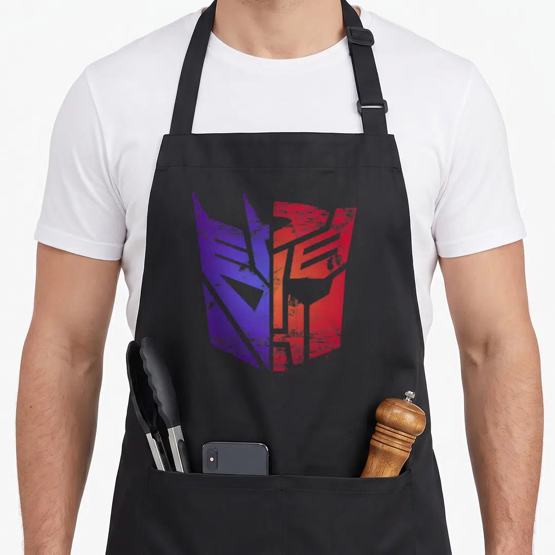 Autobot split apron - Distressed robot face logo split vertically into purple and red halves centered on apron front — shown on a black cotton canvas apron against a white background