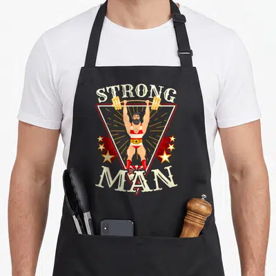 Strongman circus apron - Cartoon strongman lifting barbell in red white triangle with STRONG MAN text — shown on a black cotton canvas apron against a white background