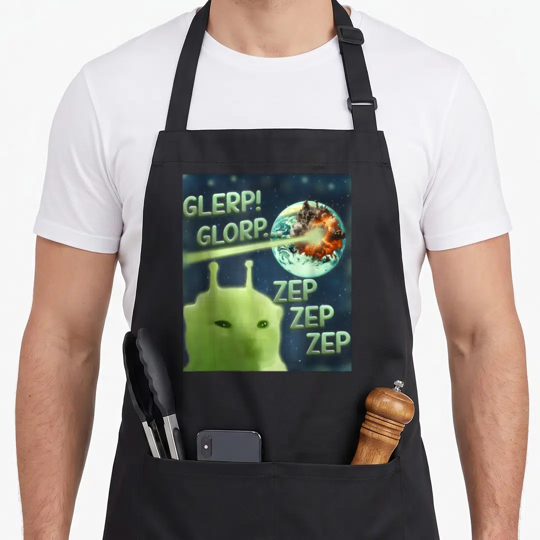 Glerp cat apron - Green alien shoots laser at exploding planet with GLERP GLORP ZEP text — shown on a black cotton canvas apron against a white background