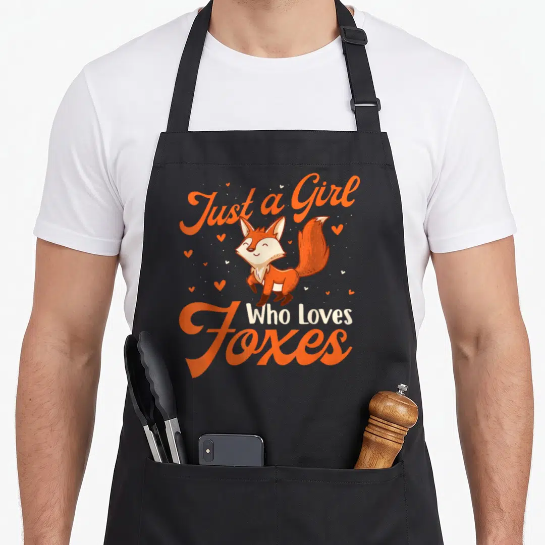 Zookeeper fox aprons - Cartoon fox illustration with orange script text and scattered hearts — shown on a black cotton canvas apron against a white background