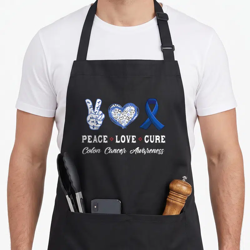 Peace colon cancer awareness apron - Blue ribbon peace sign heart and Cure text in cartoon style — shown on a black cotton canvas apron against a white background
