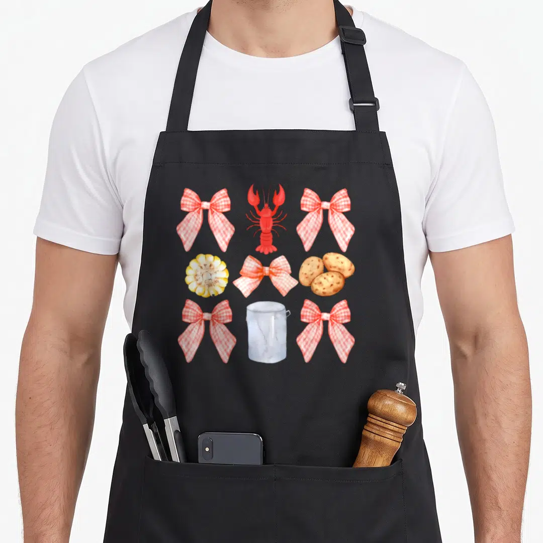 Bow crawfish boil apron - Red lobster, yellow corn, brown potatoes, marble pot, and four red white gingham bows — shown on a black cotton canvas apron against a white background