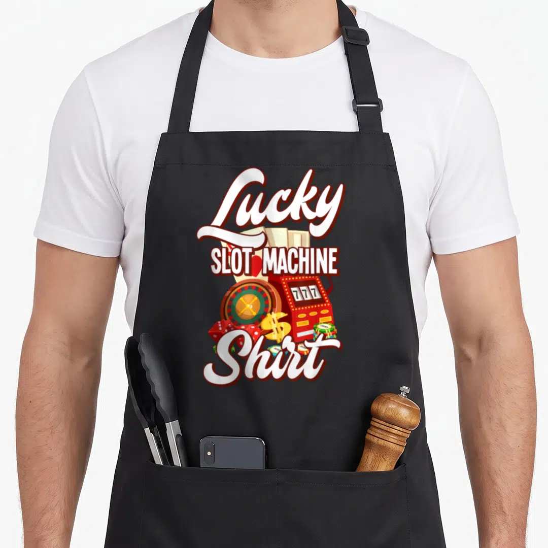 Las casino aprons - Lucky Slot Machine Shirt text with slot machine, roulette wheel, dice, chips, and cards in cartoon — shown on a black cotton canvas apron against a white background
