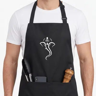 Ganesha diwali apron - Minimalist white line art of Ganesha head centered on black background — shown on a black cotton canvas apron against a white background