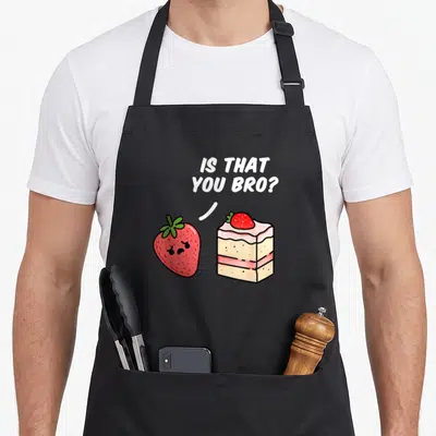Bro cake apron - Cartoon strawberry and cake slice with text IS THAT YOU BRO in red white beige — shown on a black cotton canvas apron against a white background