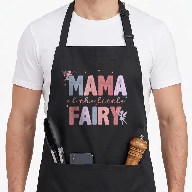 Fairy family aprons - MAMA of the little FAIRY text with two fairies and sparkles in pink blue purple red — shown on a black cotton canvas apron against a white background