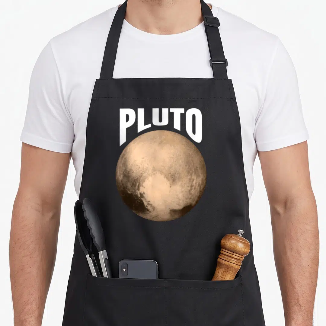 Pluto planets apron - Realistic tan and brown planet with white PLUTO text overlapping the top — shown on a black cotton canvas apron against a white background