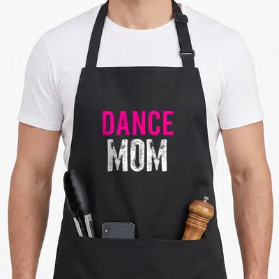 Dancer ballet dance apron - Pink DANCE and distressed white MOM text stacked vertically on dark background — shown on a black cotton canvas apron against a white background