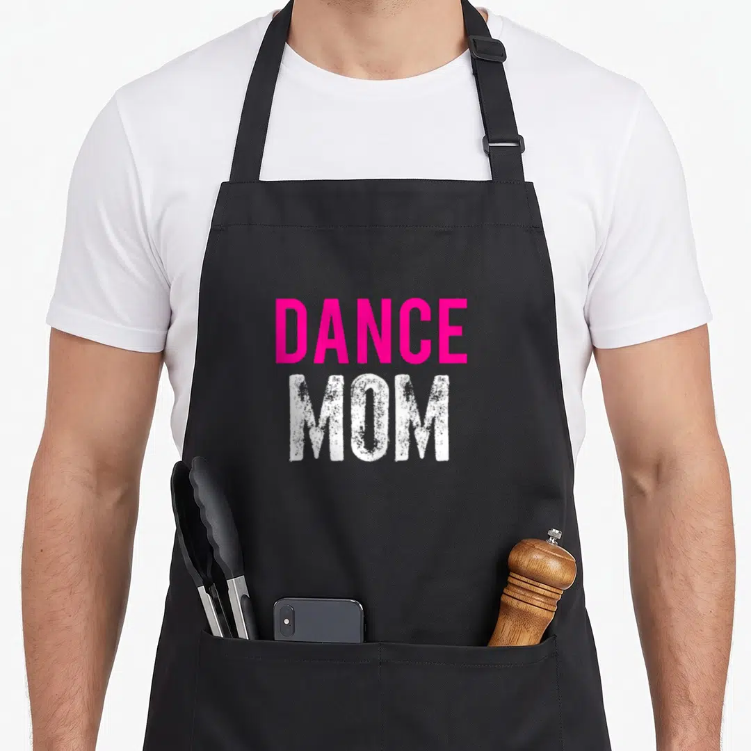 Dancer ballet dance apron - Pink DANCE and distressed white MOM text stacked vertically on dark background — shown on a black cotton canvas apron against a white background