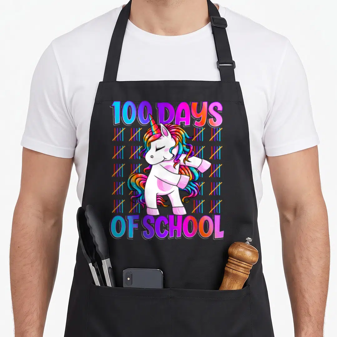 Smarter unicorn apron - Cartoon unicorn dabbing with 100 DAYS OF SCHOOL text and rainbow tally marks — shown on a black cotton canvas apron against a white background