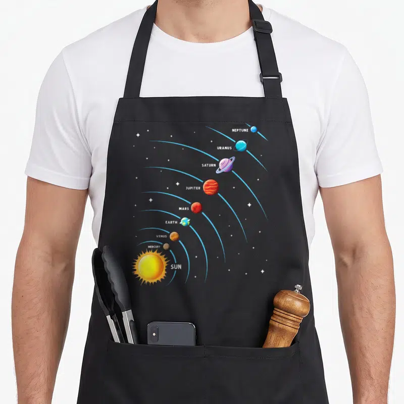 Solar colorful aprons - Labeled solar system planets and sun on blue orbits with cartoon graphics on grey background — shown on a black cotton canvas apron against a white background
