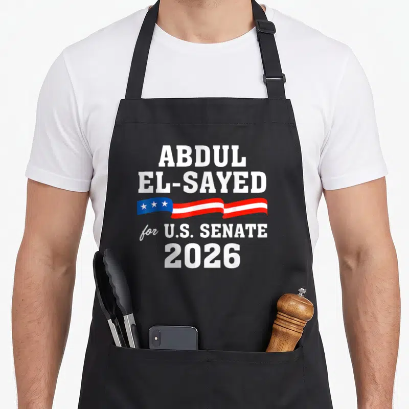 Abdul senator apron - ABDUL EL-SAYED for U.S. SENATE 2026 text with red white blue star ribbon — shown on a black cotton canvas apron against a white background