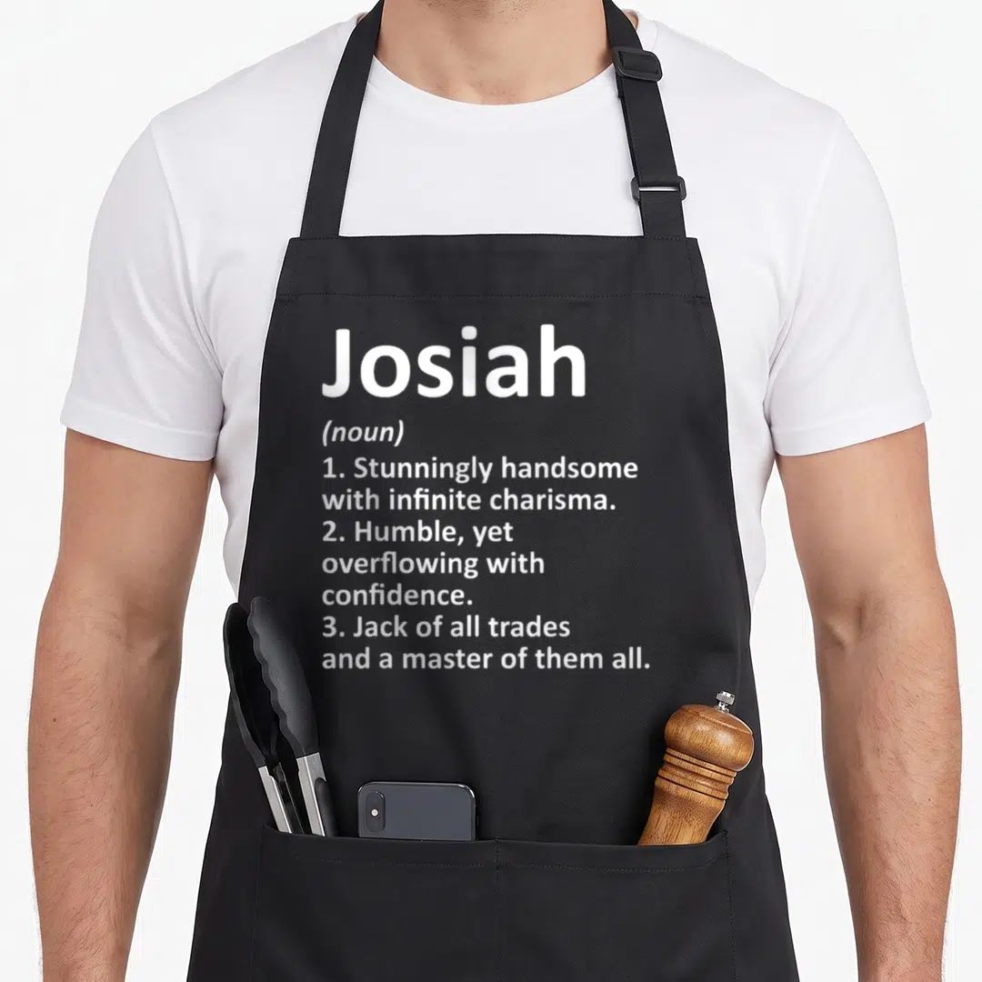 Josiah father day aprons - White typography listing three definitions for Josiah including handsome and master of all — shown on a black cotton canvas apron against a white background