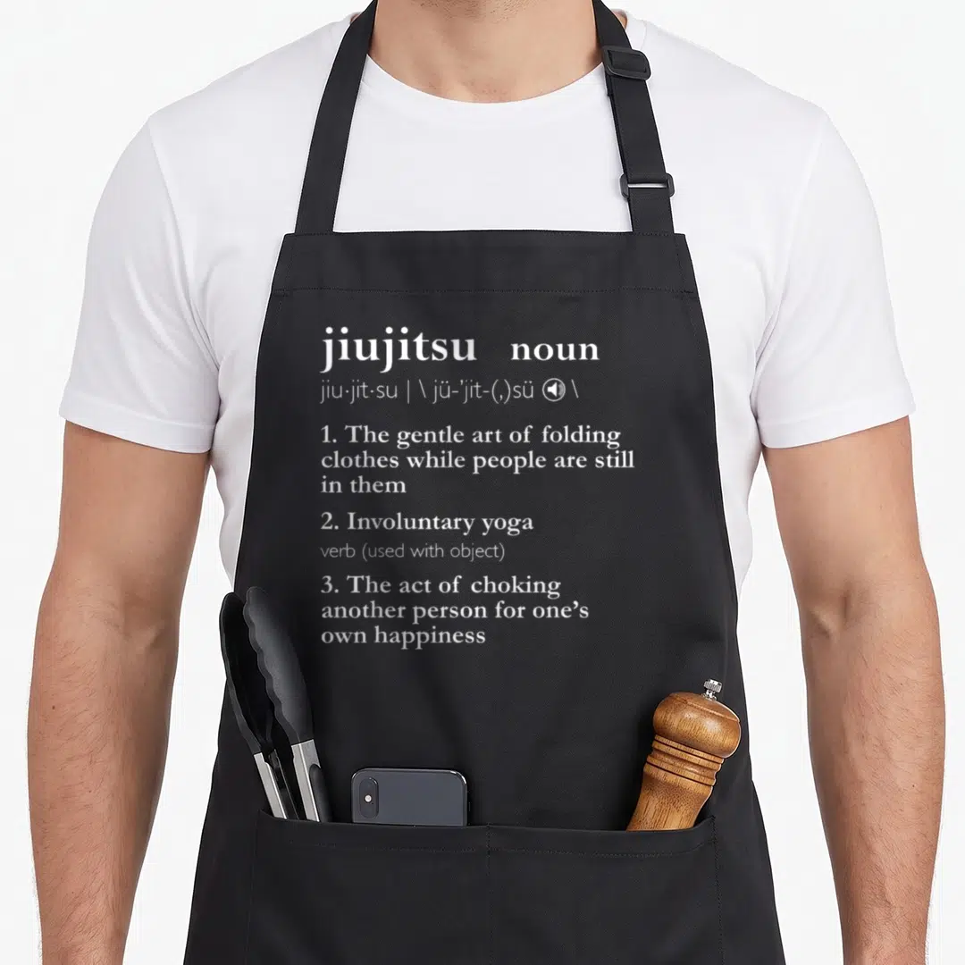 Brazilian jitsu apron - White dictionary definition of jiujitsu listing folding clothes and involuntary yoga as — shown on a black cotton canvas apron against a white background