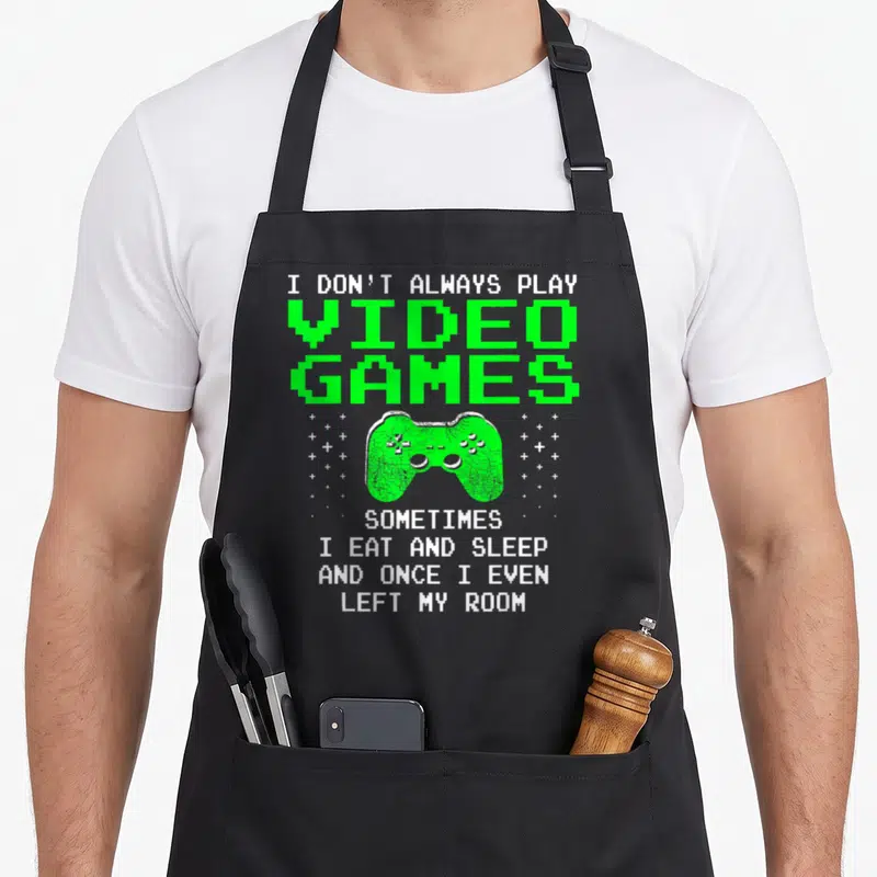 Alway play gaming apron - Green pixel art game controller with white text about eating and sleeping — shown on a black cotton canvas apron against a white background