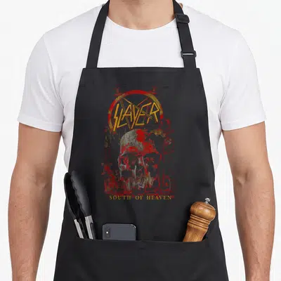 South slayer apron - SLAYER logo over red pentagram with distressed hellish illustration and SOUTH OF HEAVEN text — shown on a black cotton canvas apron against a white background