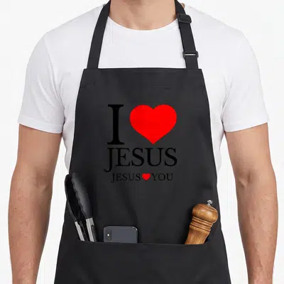 Vintage jesus christian apron - Black text reading I JESUS JESUS YOU with two red hearts on a dark background — shown on a black cotton canvas apron against a white background