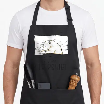 Sleepshirt bear apron - Cartoon polar bear lying on white pillow above black text reading FAVORITE SLEEPSHIRT — shown on a black cotton canvas apron against a white background