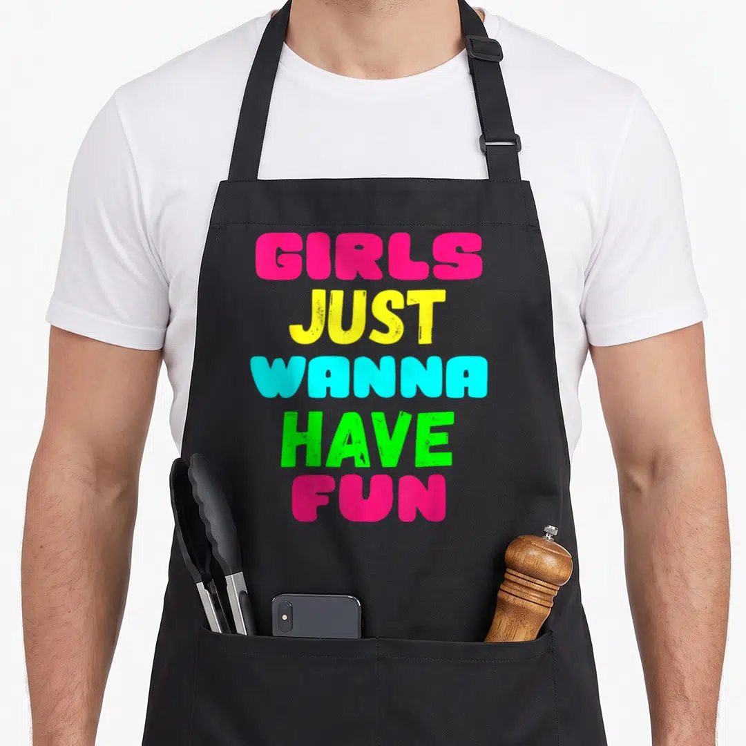 Cool general novelty apron for grilling - Stacked pink yellow cyan and green text reading GIRLS JUST WANNA HAVE FUN — shown on a black cotton canvas apron against a white background