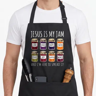 Jesus spread apron - Eight jam jars labeled love grace hope faith peace joy salvation mercy with pun text — shown on a black cotton canvas apron against a white background