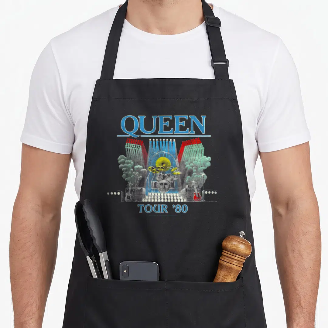 Tour queen apron - Retro concert stage art with QUEEN and TOUR '80 text in blue, red, green, grey — shown on a black cotton canvas apron against a white background