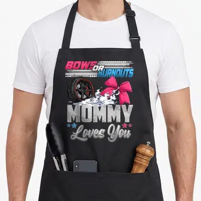 Gender bow apron - BOWS OR BURNOUTS MOMMY Loves You text with car wheel, pink bow, smoke, and stars in cartoon style — shown on a black cotton canvas apron against a white background
