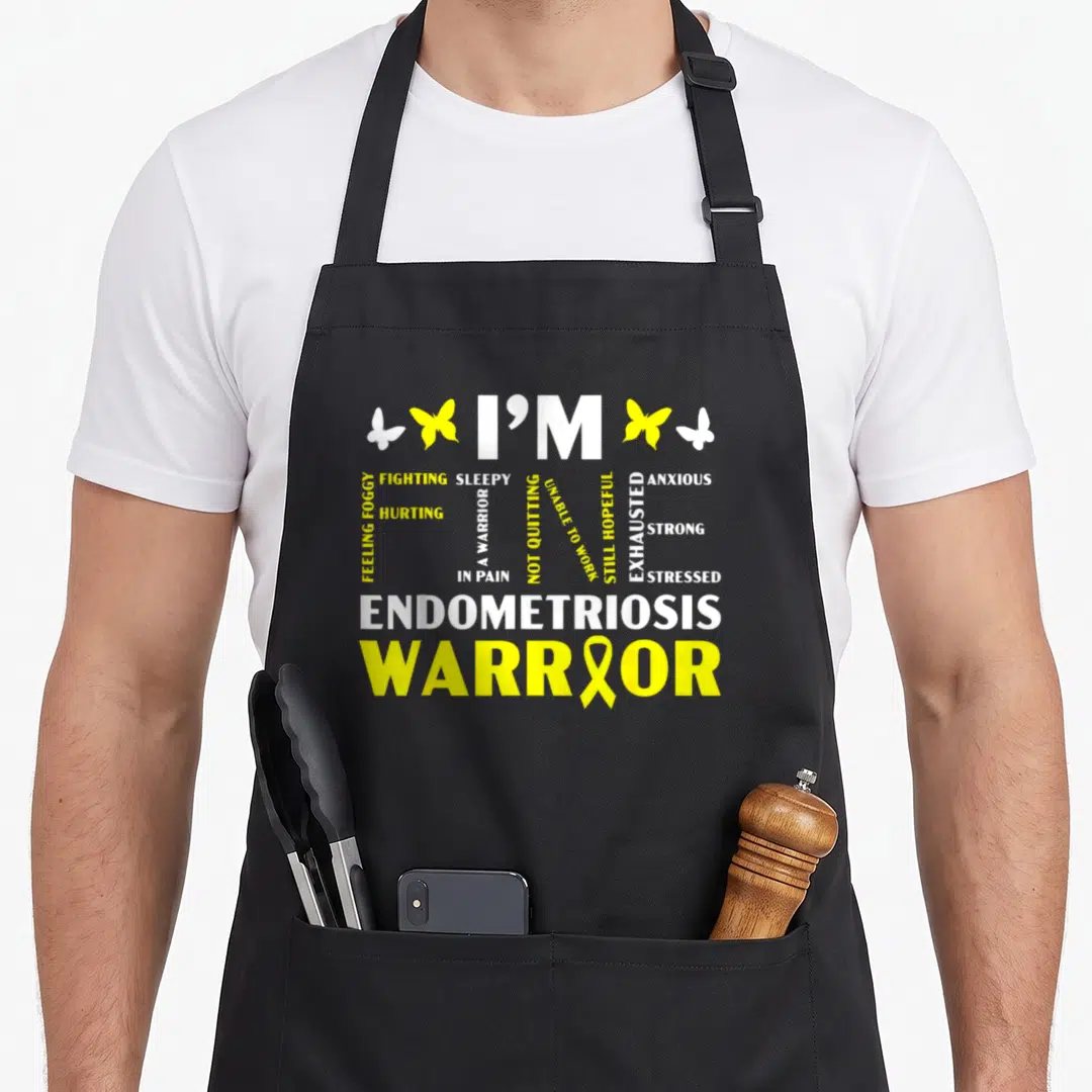 Fine endometriosis awareness apron - I'M FINE typography with yellow butterflies and Endometriosis Warrior ribbon text — shown on a black cotton canvas apron against a white background