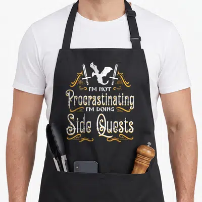 Rpg dungeon apron - Dragon and two swords above stacked text reading I'M NOT Procrastinating I'M DOING Side Quests — shown on a black cotton canvas apron against a white background