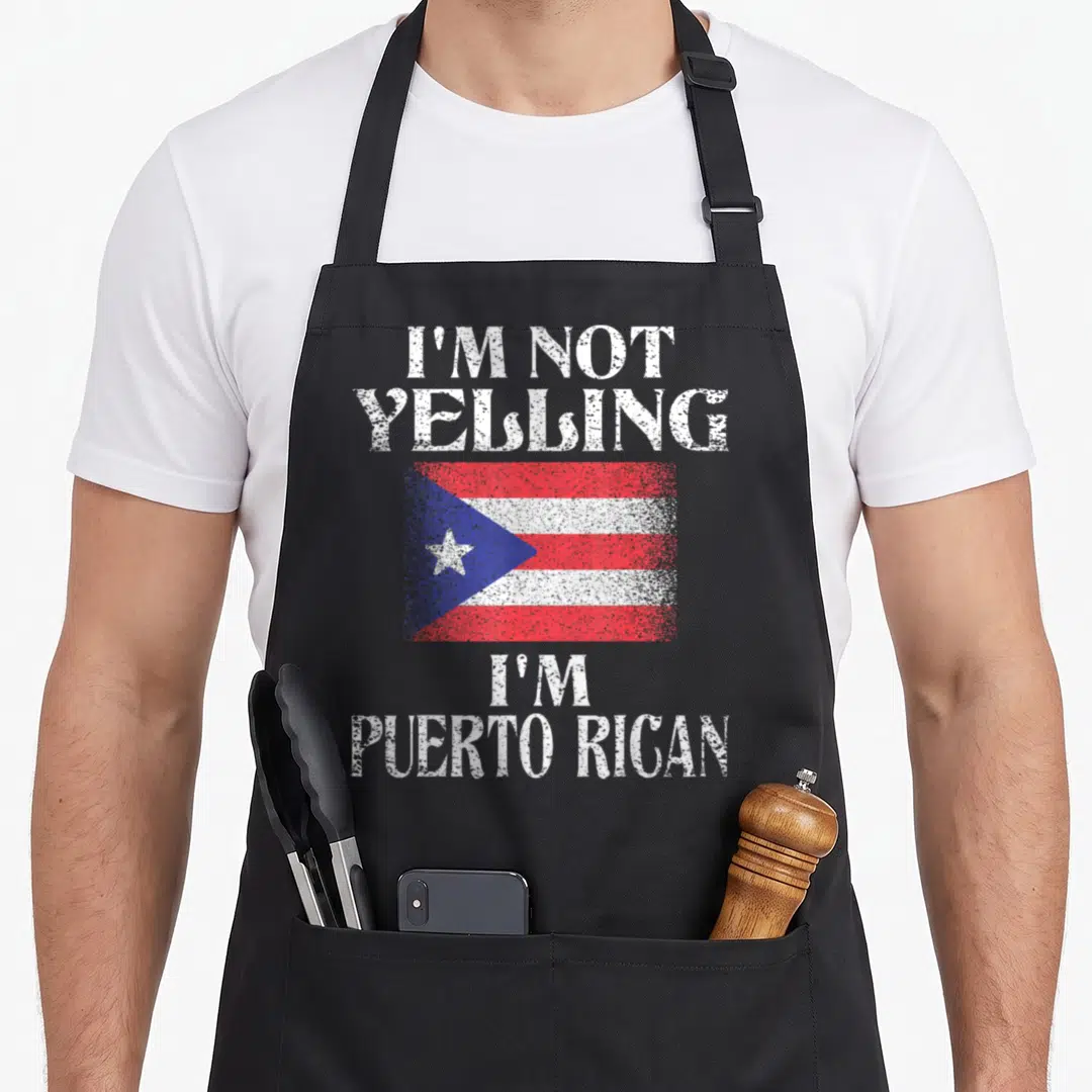 Puerto rican pride apron - Distressed Puerto Rican flag between I'm Not Yelling and I'm Puerto Rican text — shown on a black cotton canvas apron against a white background