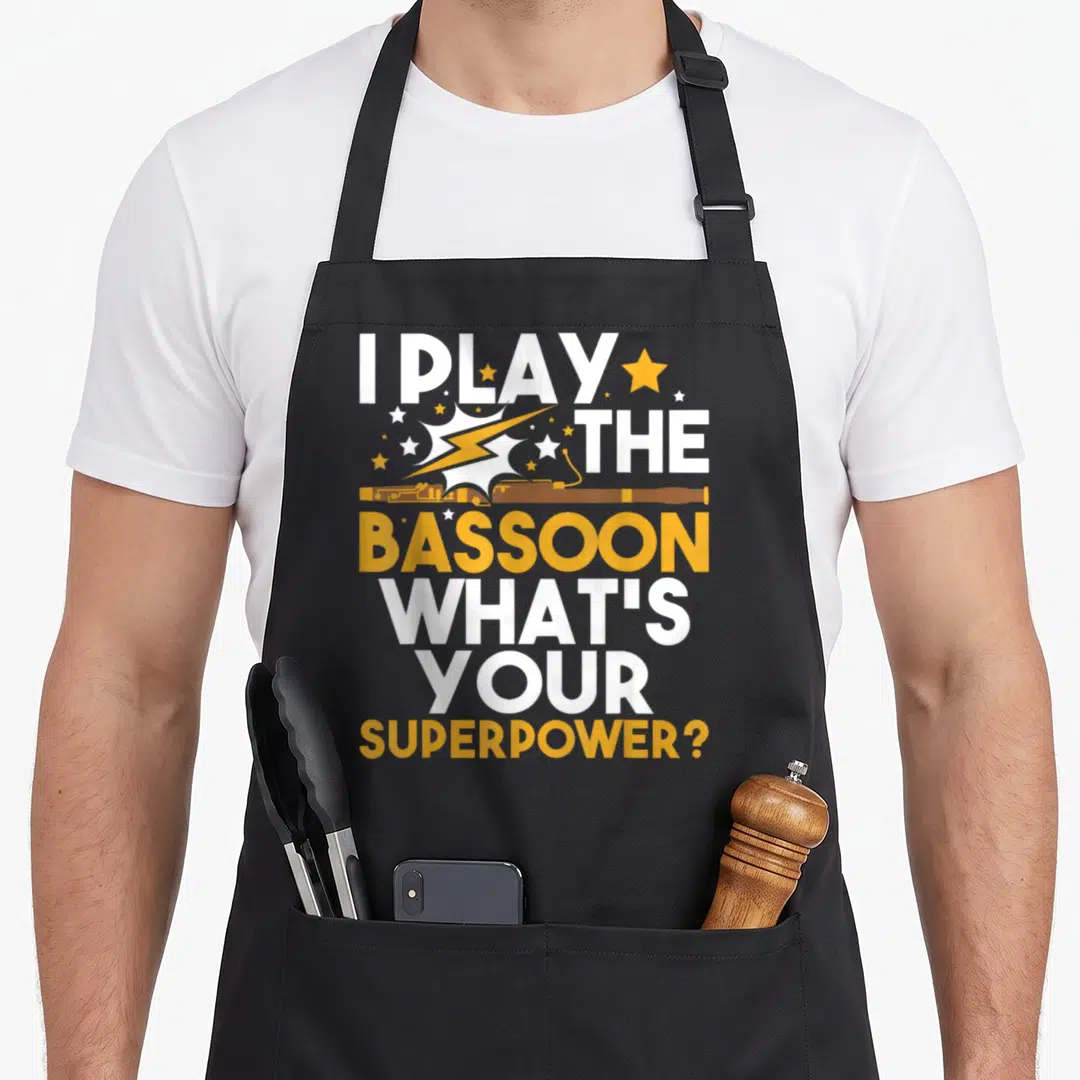 Play bassoon apron - I Play The Bassoon What's Your Superpower? with horizontal instrument and stars — shown on a black cotton canvas apron against a white background