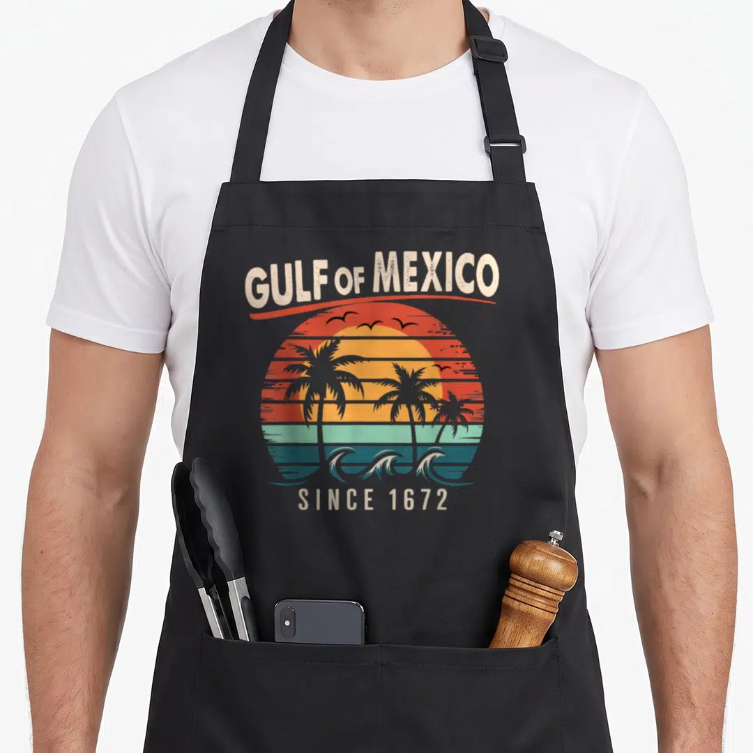 Vintage gulf mexico apron - Retro sunset with palm trees and waves under arched text reading GULF of MEXICO SINCE 1672 — shown on a black cotton canvas apron against a white background