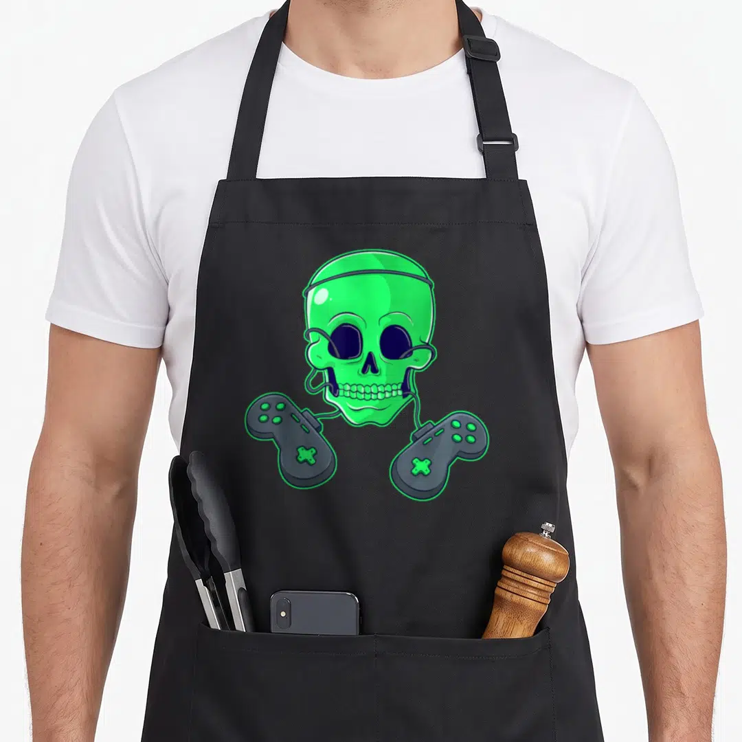 Skeleton skull halloween apron - Green skull with grey controllers connected by wires in cartoon style — shown on a black cotton canvas apron against a white background