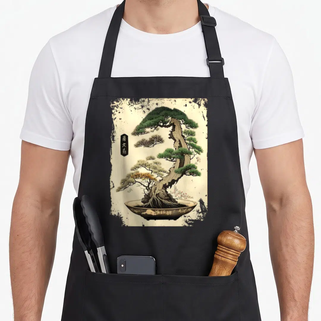 Garden japan apron - Realistic bonsai tree in a pot with vertical Japanese characters on a beige background — shown on a black cotton canvas apron against a white background