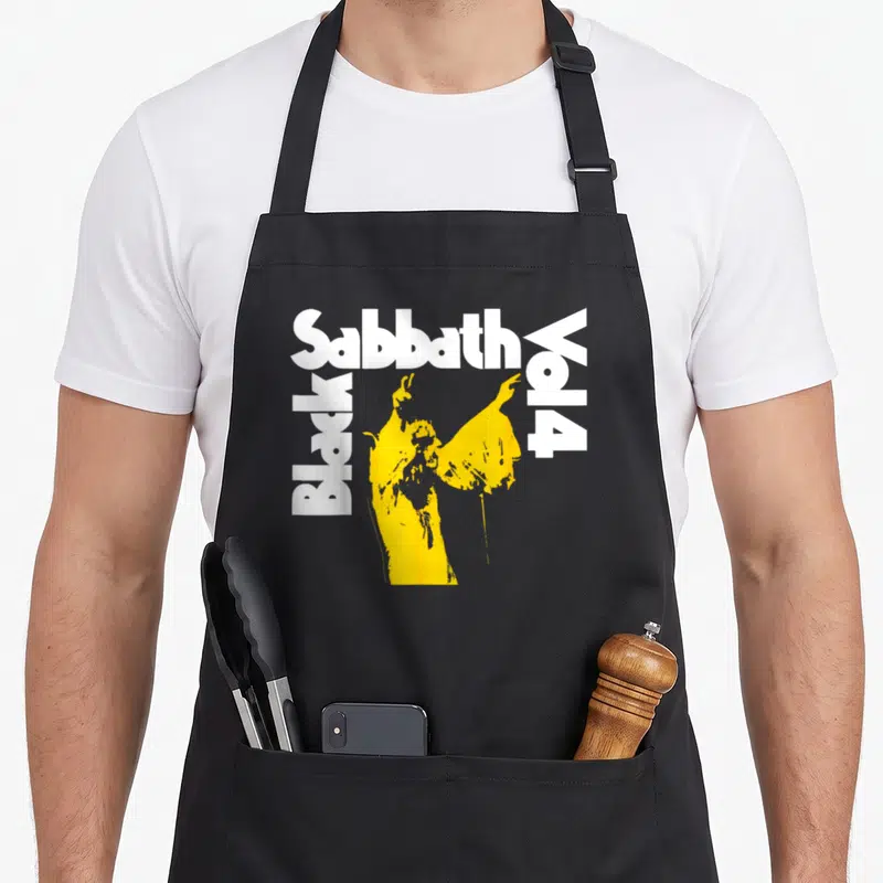 Vol black officially apron - Yellow singer silhouette framed by white Sabbath Black Vol 4 text — shown on a black cotton canvas apron against a white background