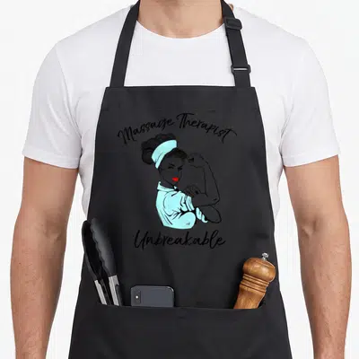 Unbreakable massage therapy apron - Cartoon woman flexing arm with Massage Therapist Unbreakable text in blue and red — shown on a black cotton canvas apron against a white background
