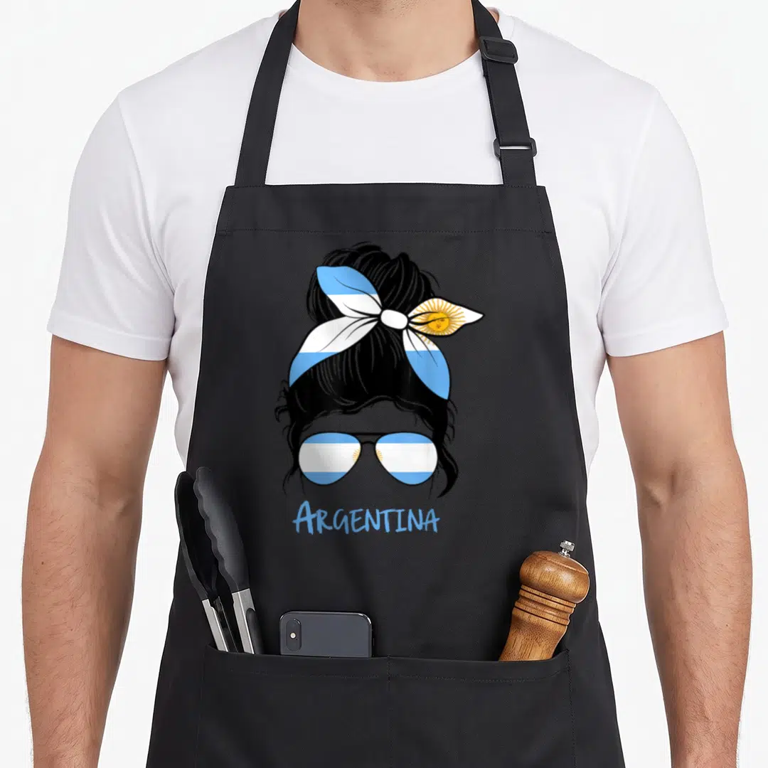 Argentine bandana apron - Black silhouette woman with bun, sunglasses and bandana in blue white yellow flag colors — shown on a black cotton canvas apron against a white background