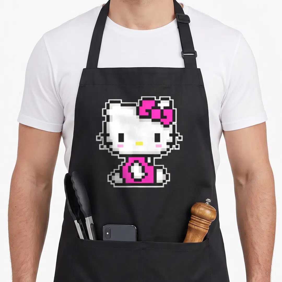Funny pixel apron - Pixel art Hello Kitty in white pink and black centered on apron front — shown on a black cotton canvas apron against a white background