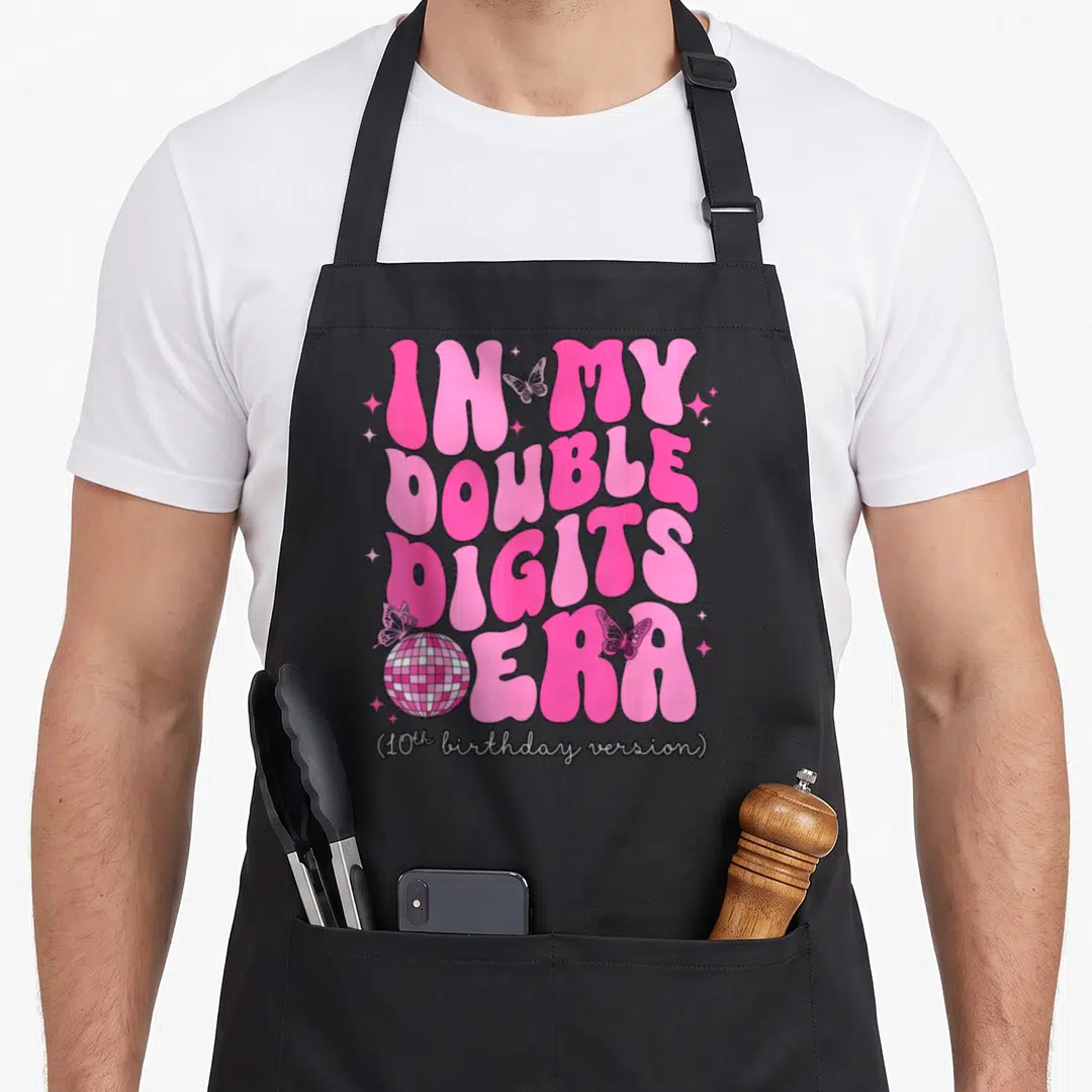 Era birthday apron - Pink bubbly text IN MY DOUBLE DIGITS ERA with disco ball and butterflies — shown on a black cotton canvas apron against a white background